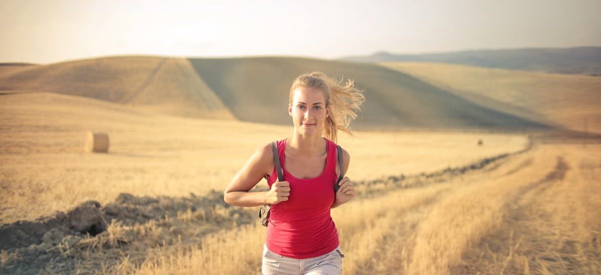 A woman jogging through vast, golden wheat fields under the summer sun, symbolizing freedom and adventure.